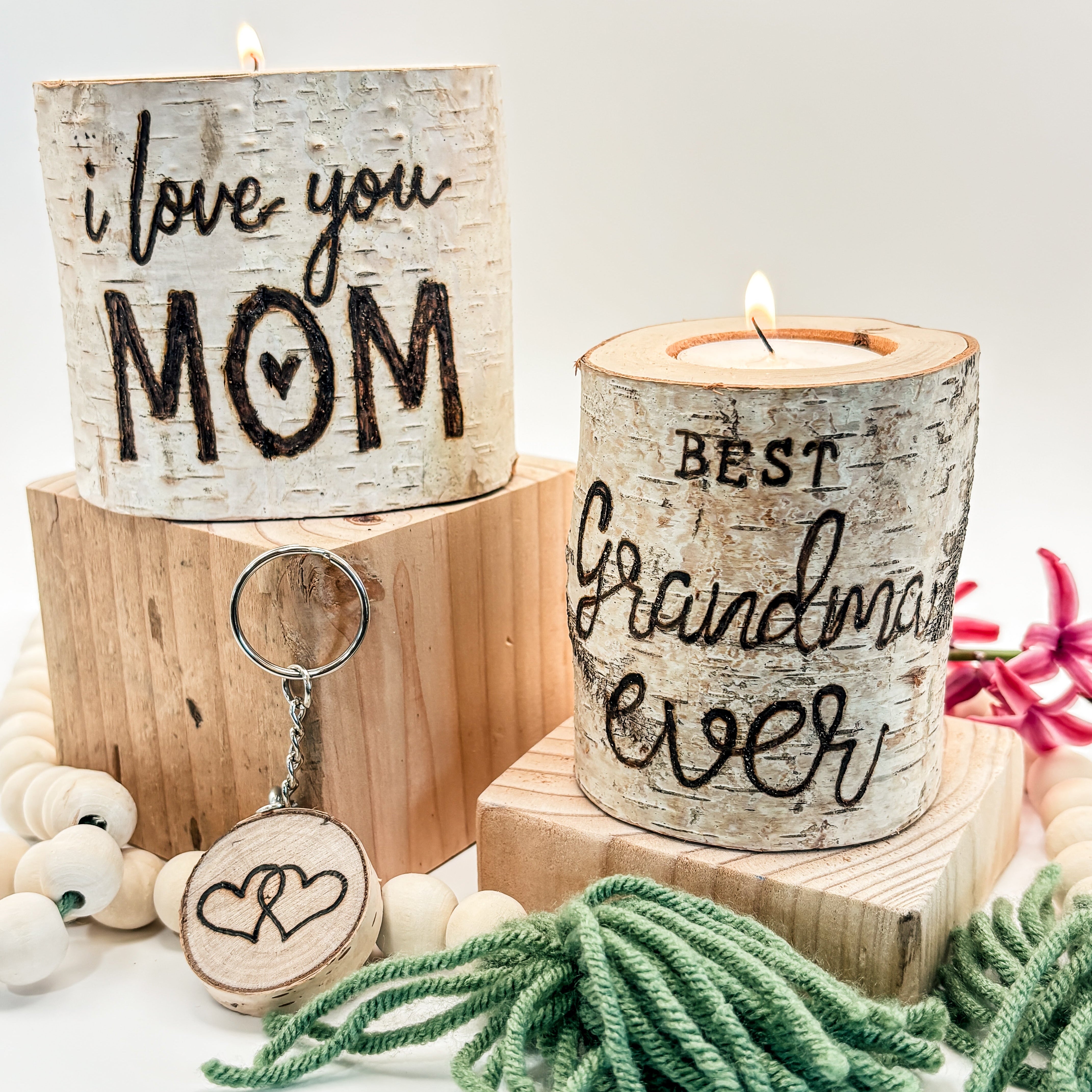 Two wooden candle holders with engraved text, a keychain, and decorative elements on a light background.
