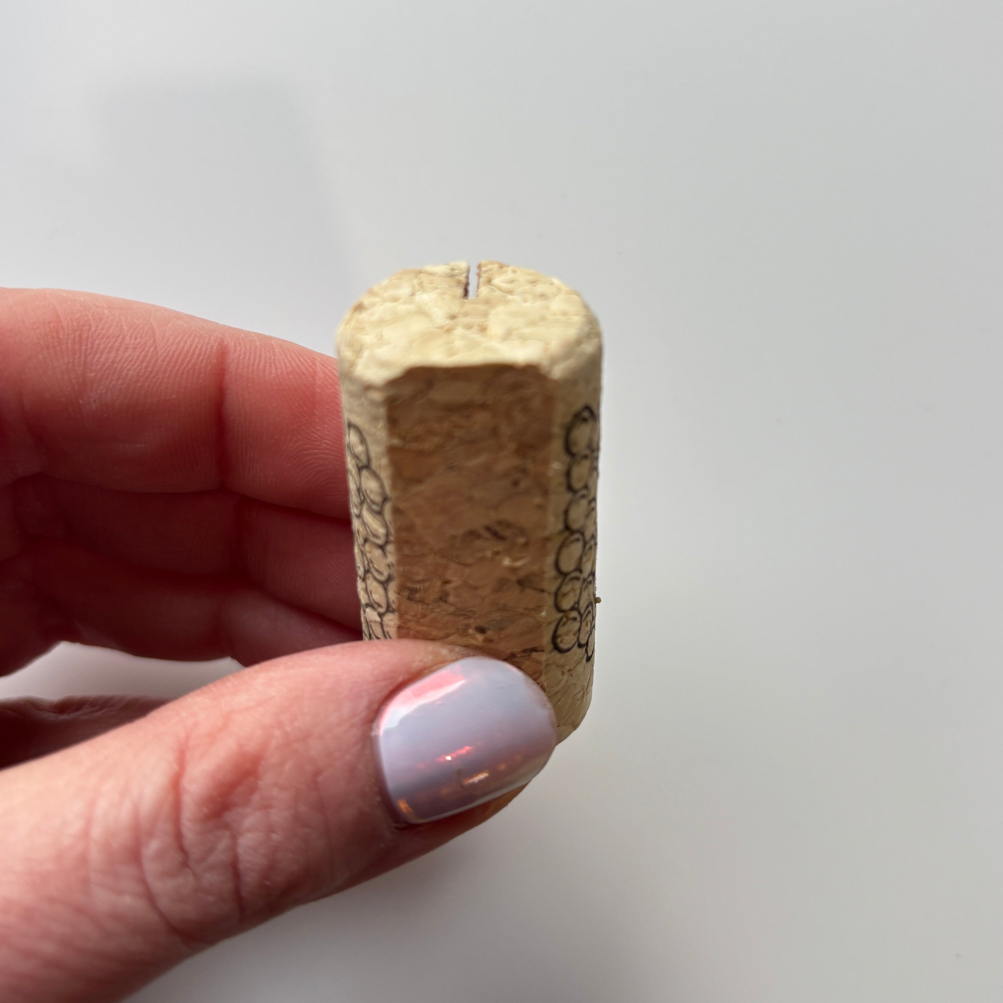 Cork place card holder held by a hand on a plain background