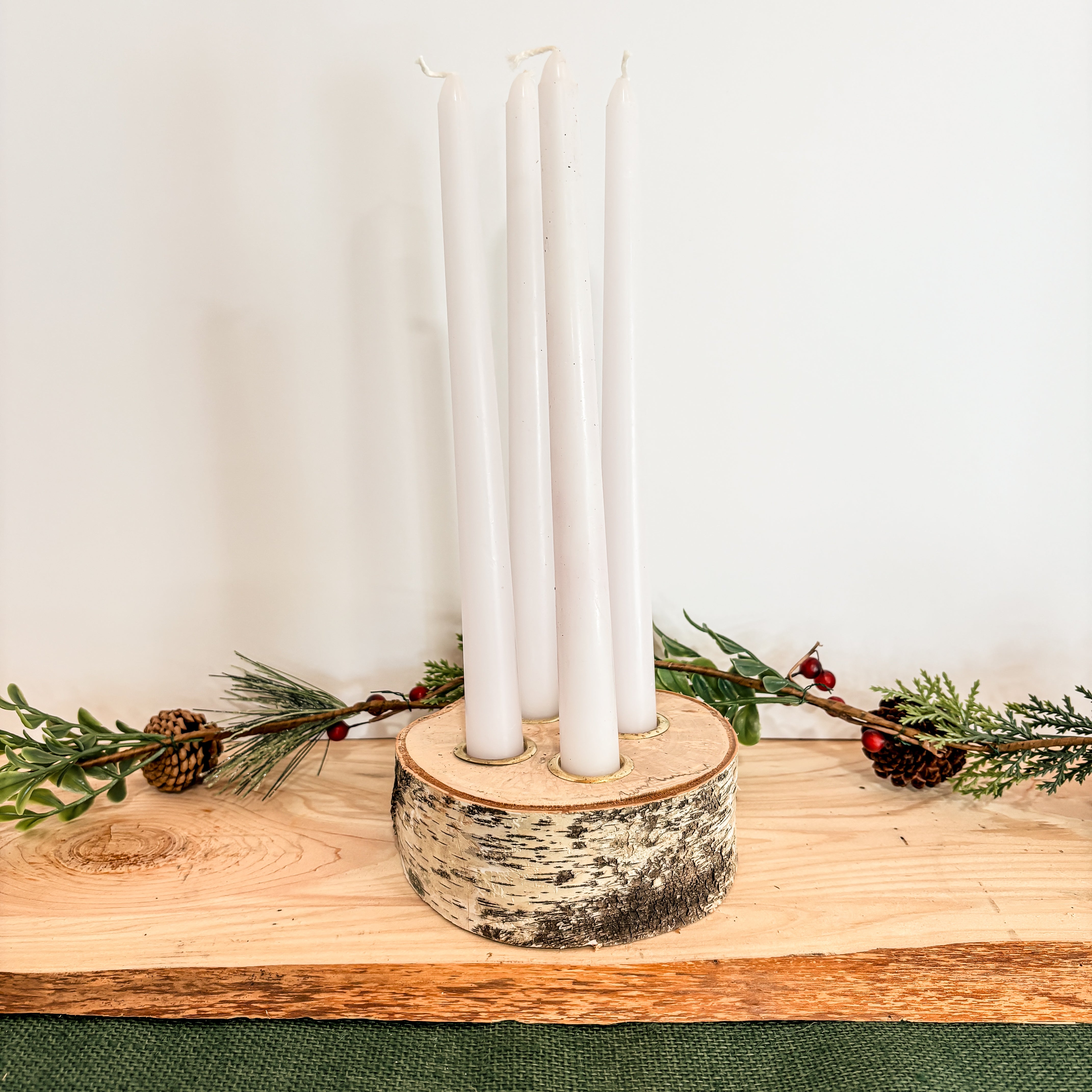 all natural birch log taper candle holder centerpiece with four white taper candles and greenery decoration perfect for a Christmas table decoration 