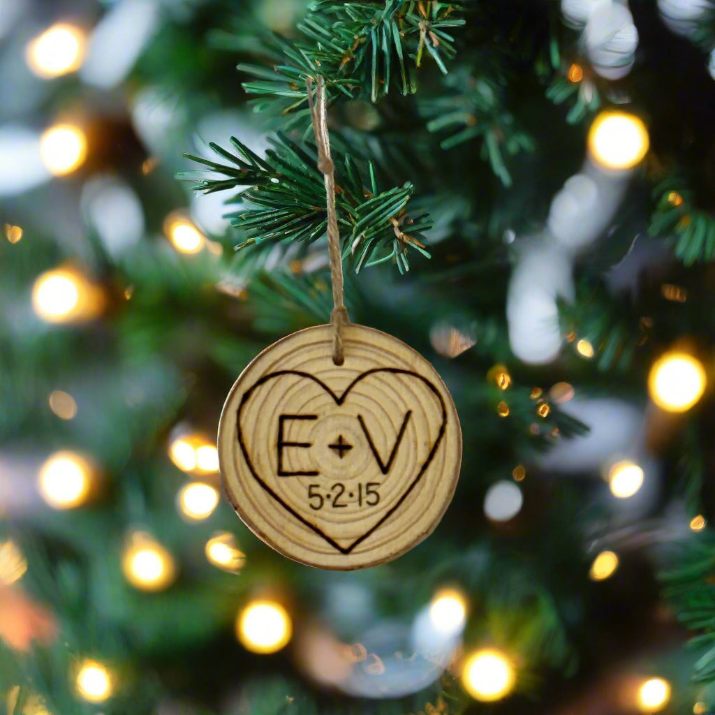 Wooden round ornament with 'E+V' and '5215' engraved in a heart shape on a white background.