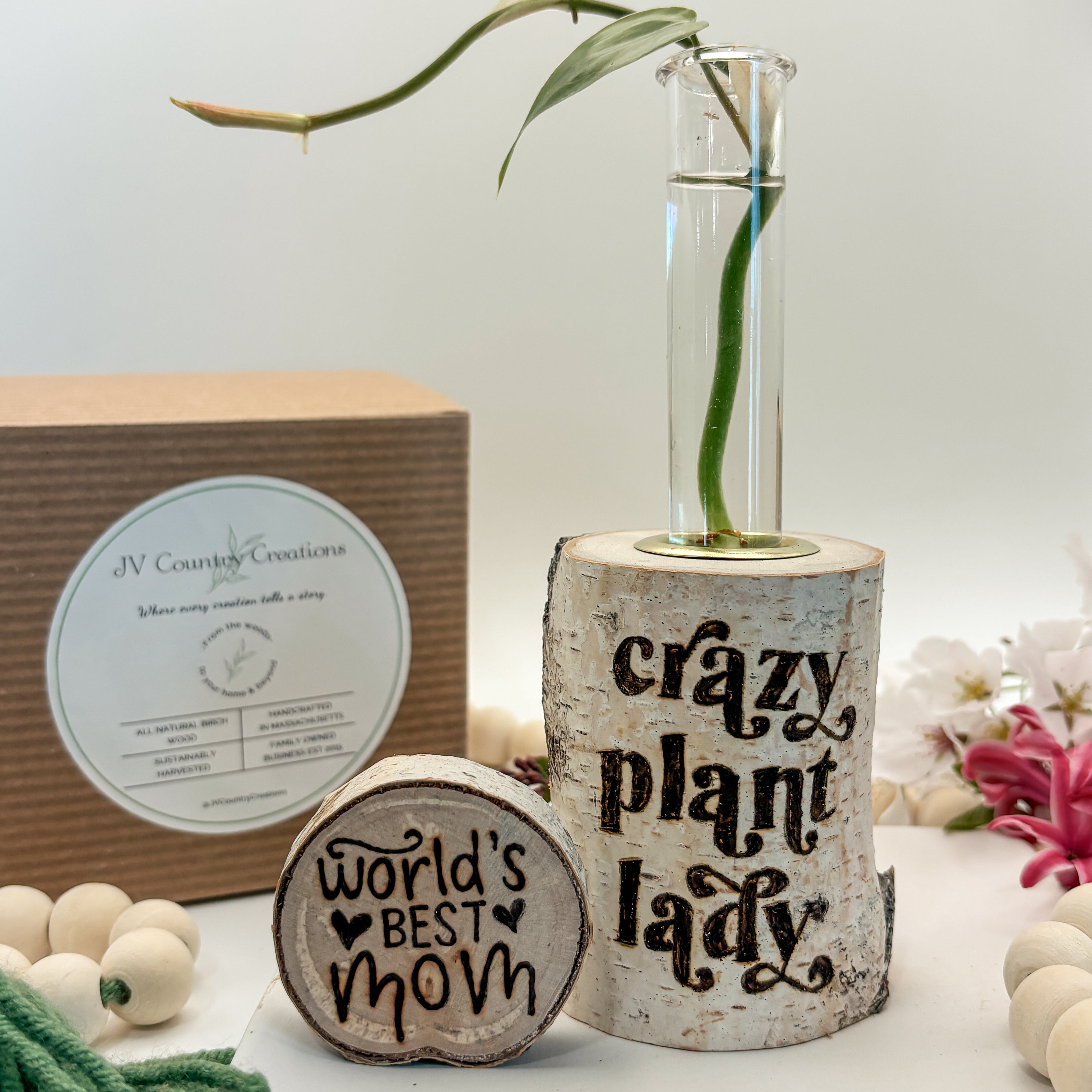 Decorative items including a vase with a plant, wooden sign, and gift box on a white surface.