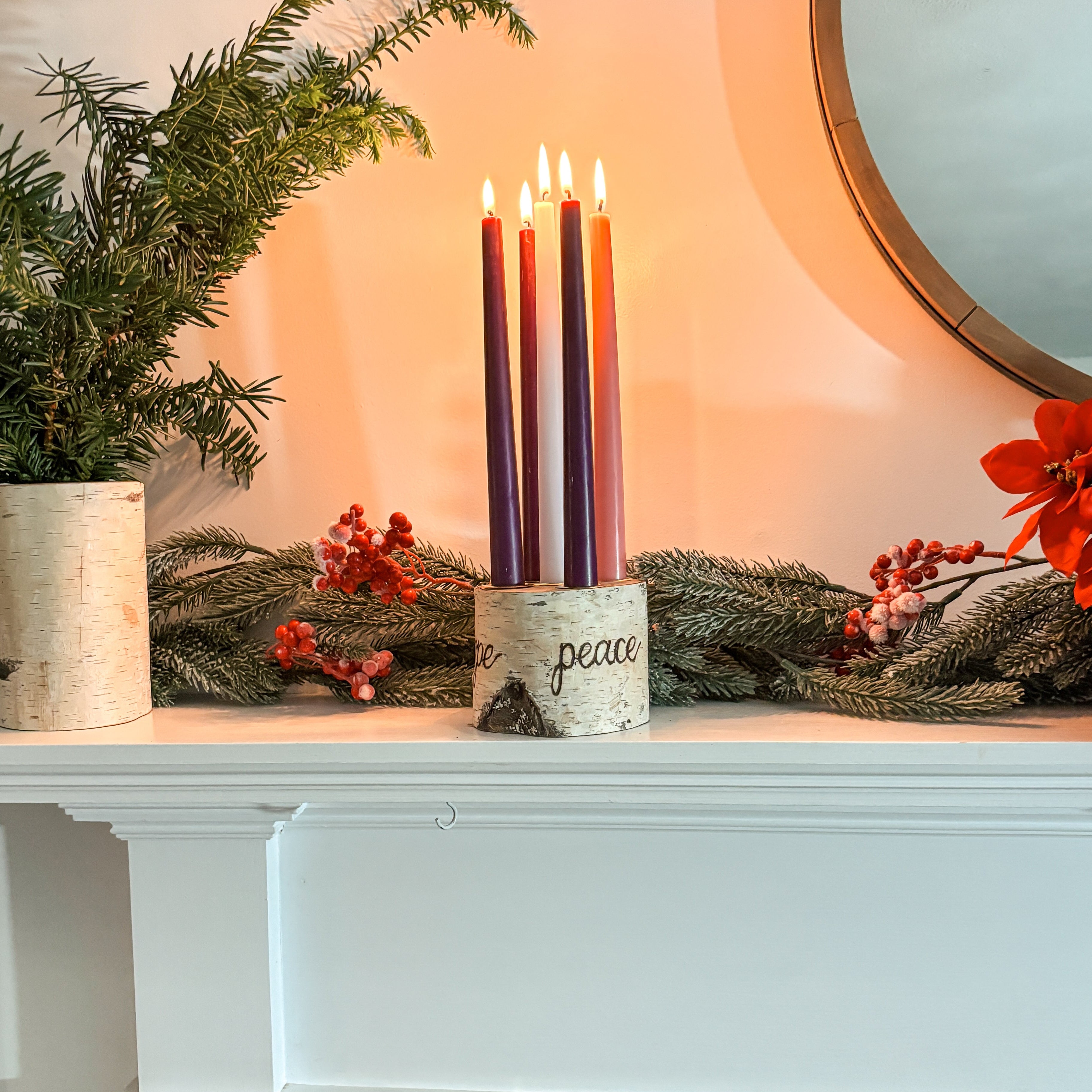 Decorative setup on a white fireplace mantel with candles, greenery, and flowers.