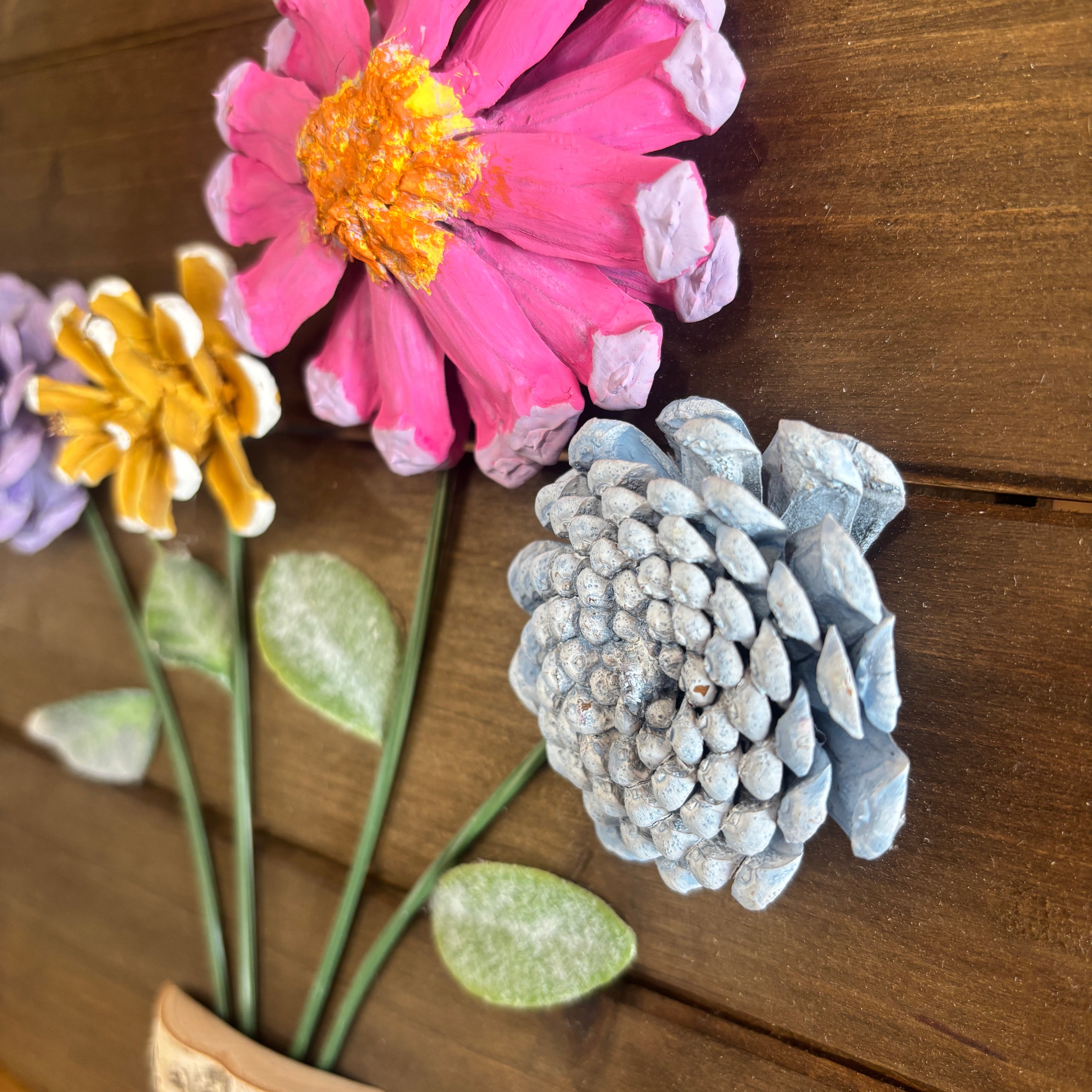 Colorful pinecone flowers on a wooden surface
