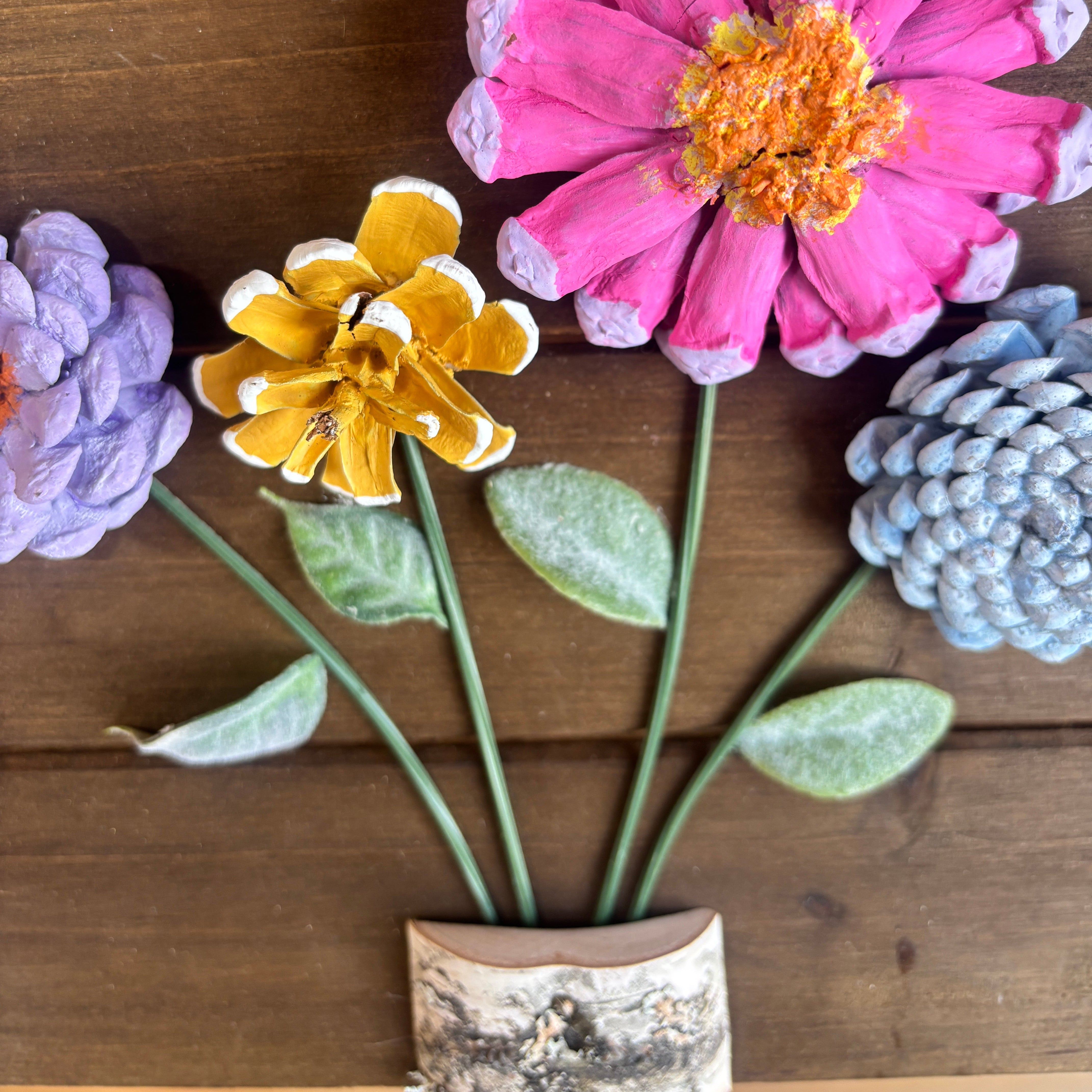 Artificial flowers and decorative elements on a wooden surface made from pinecones