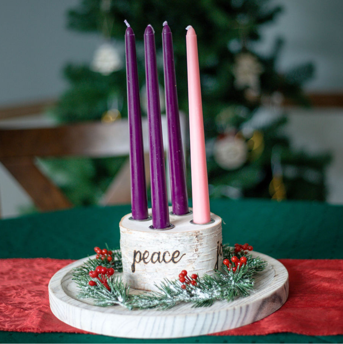 Advent wreath with four candles in front of a Christmas tree
