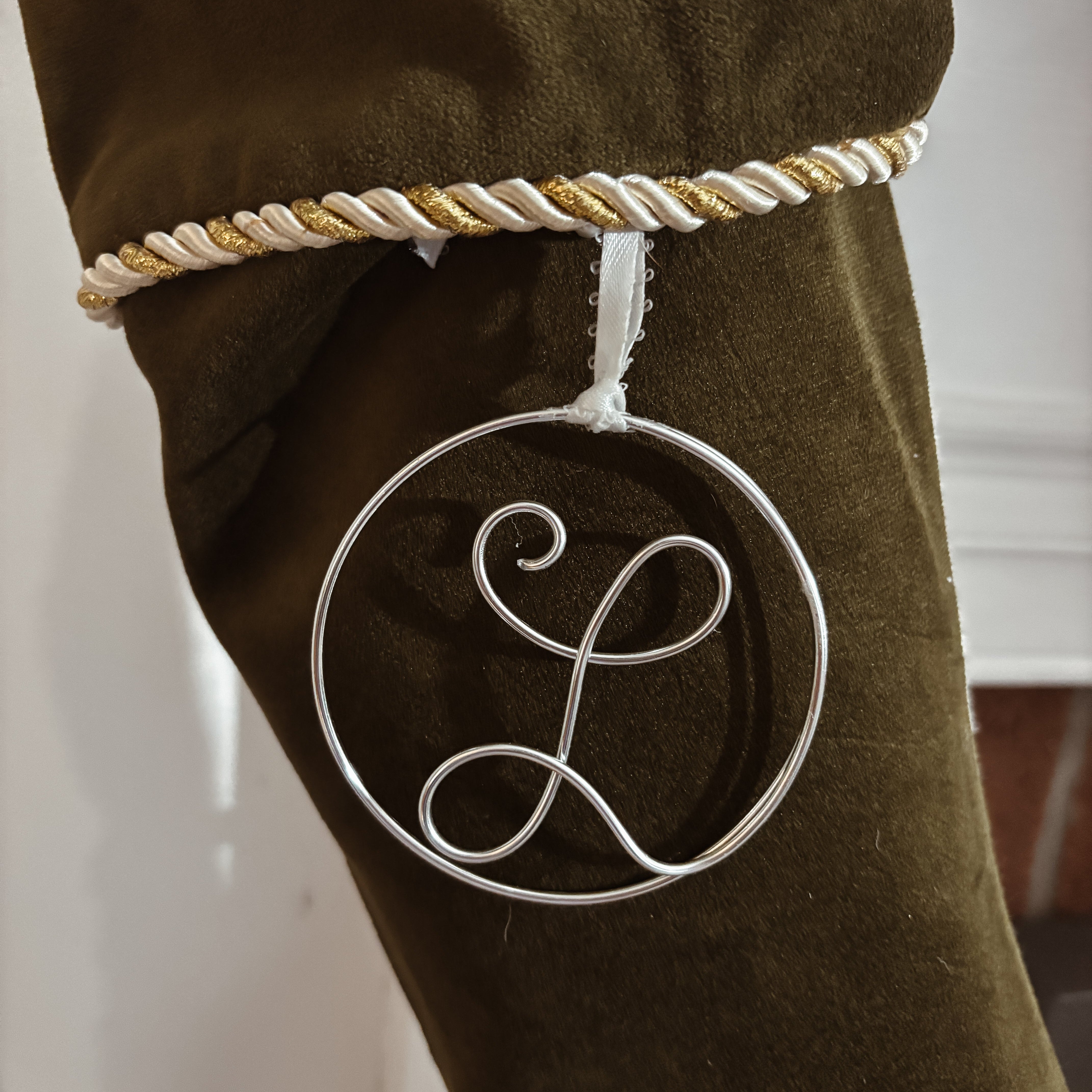 Brown stocking with a decorative silver 'L' ornament and gold and white braided trim.