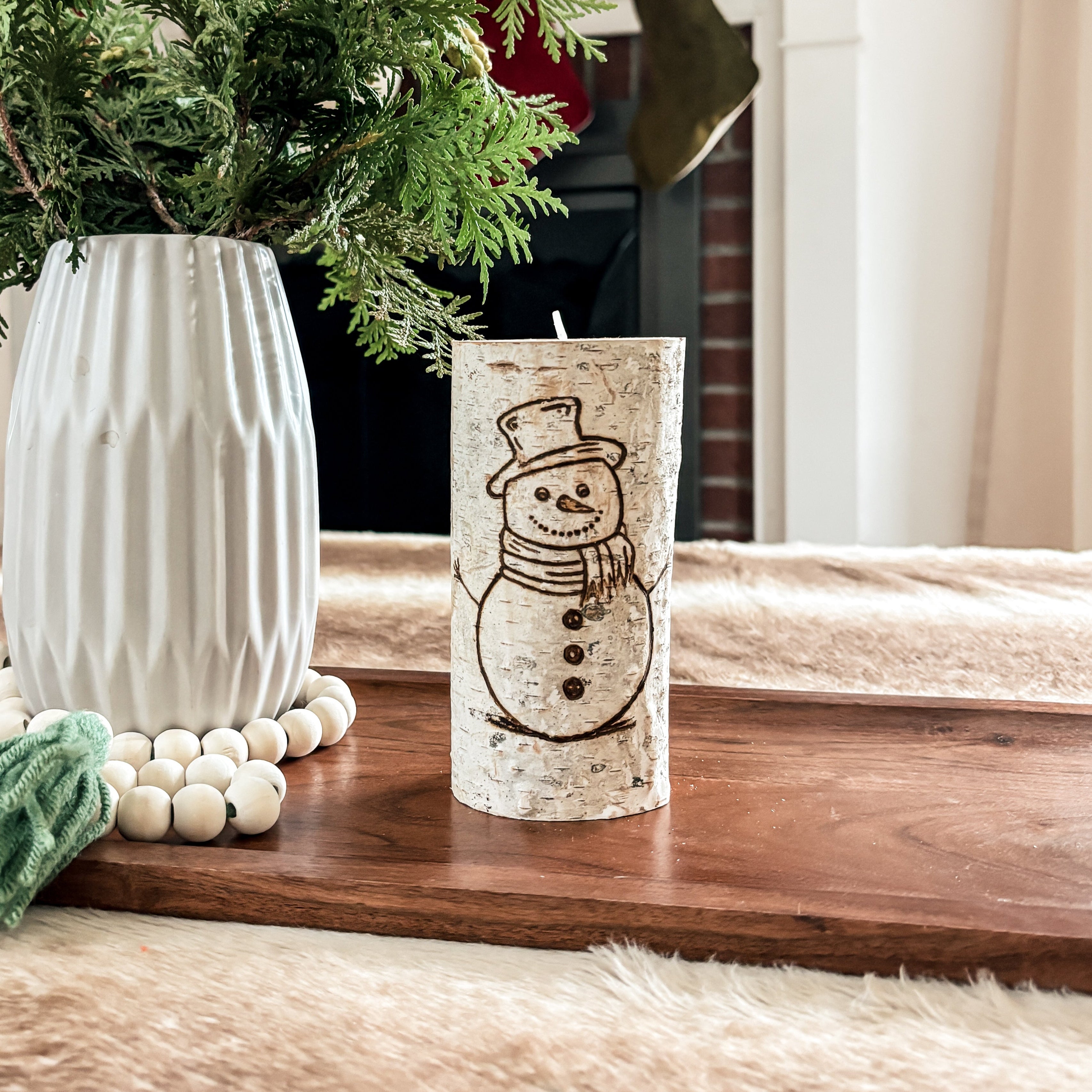 birch wood candle holder with a snowman design hand burned on the front in a Christmas decorated living room 
